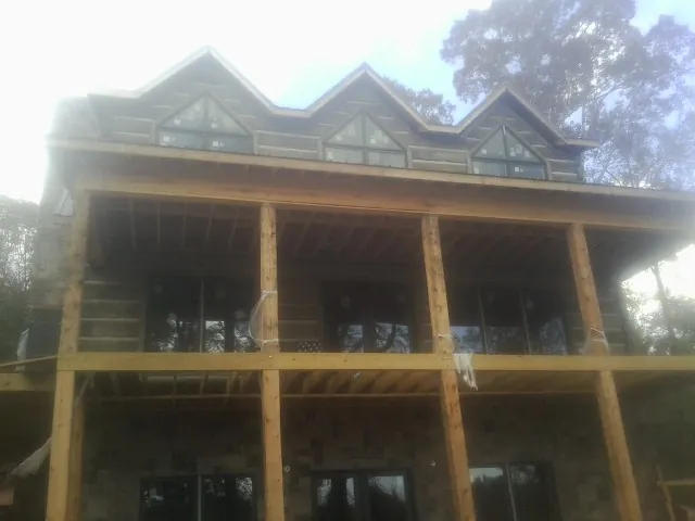 Dormers and porch framing on a large log home under construction — Roof Coating work by our crew in Oakfield
