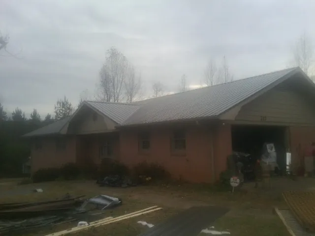 Gray metal roof on a stucco house with an attached garage in Oakfield