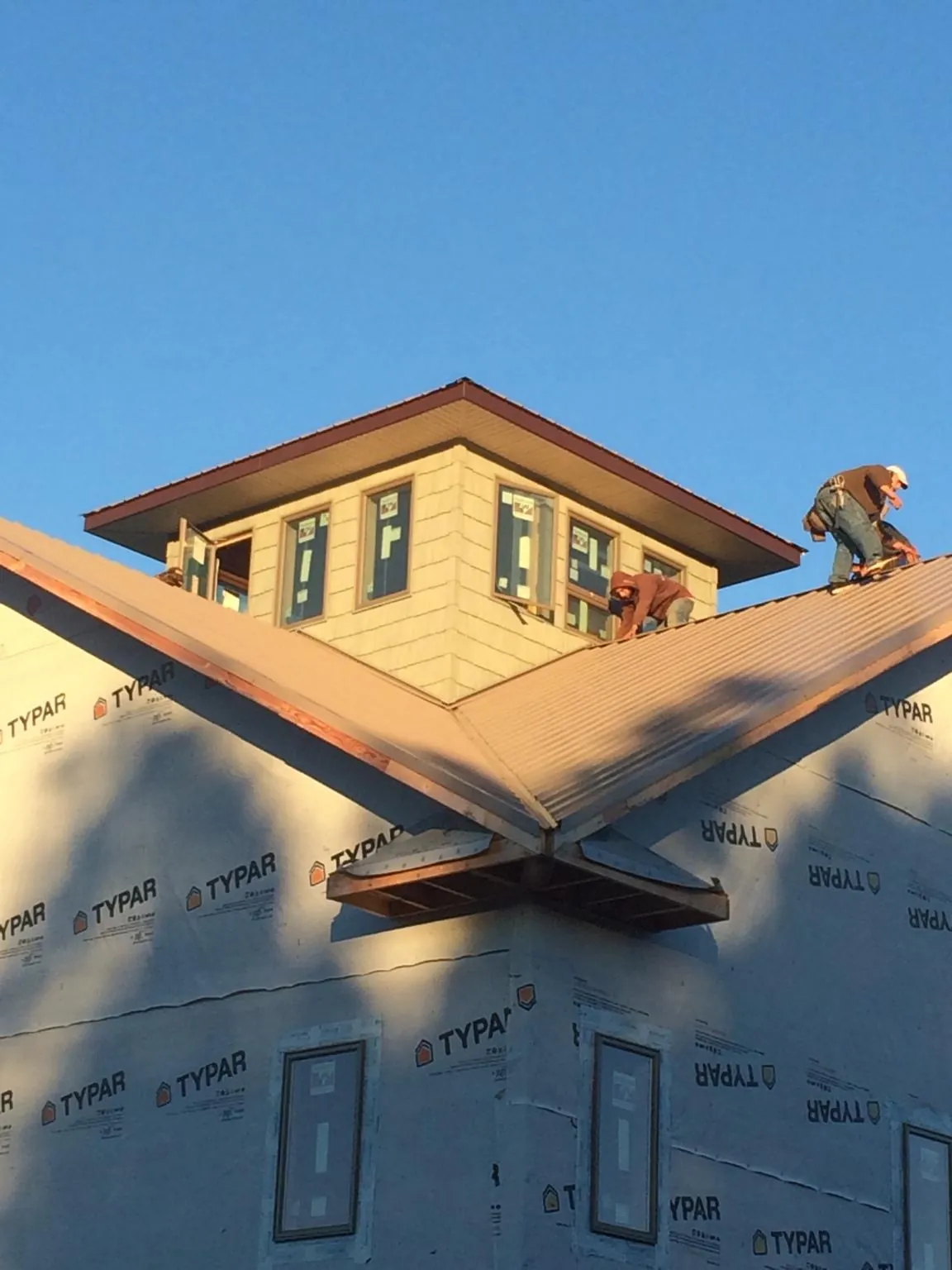 Roofers working around a rooftop cupola on a new metal roof at sunset — Roof Waterproofing in Oakfield by Roofing Brothers